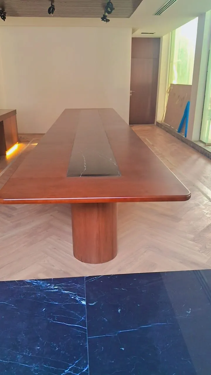 Boardroom table seen head on with a marble floor transition and greenery beyond