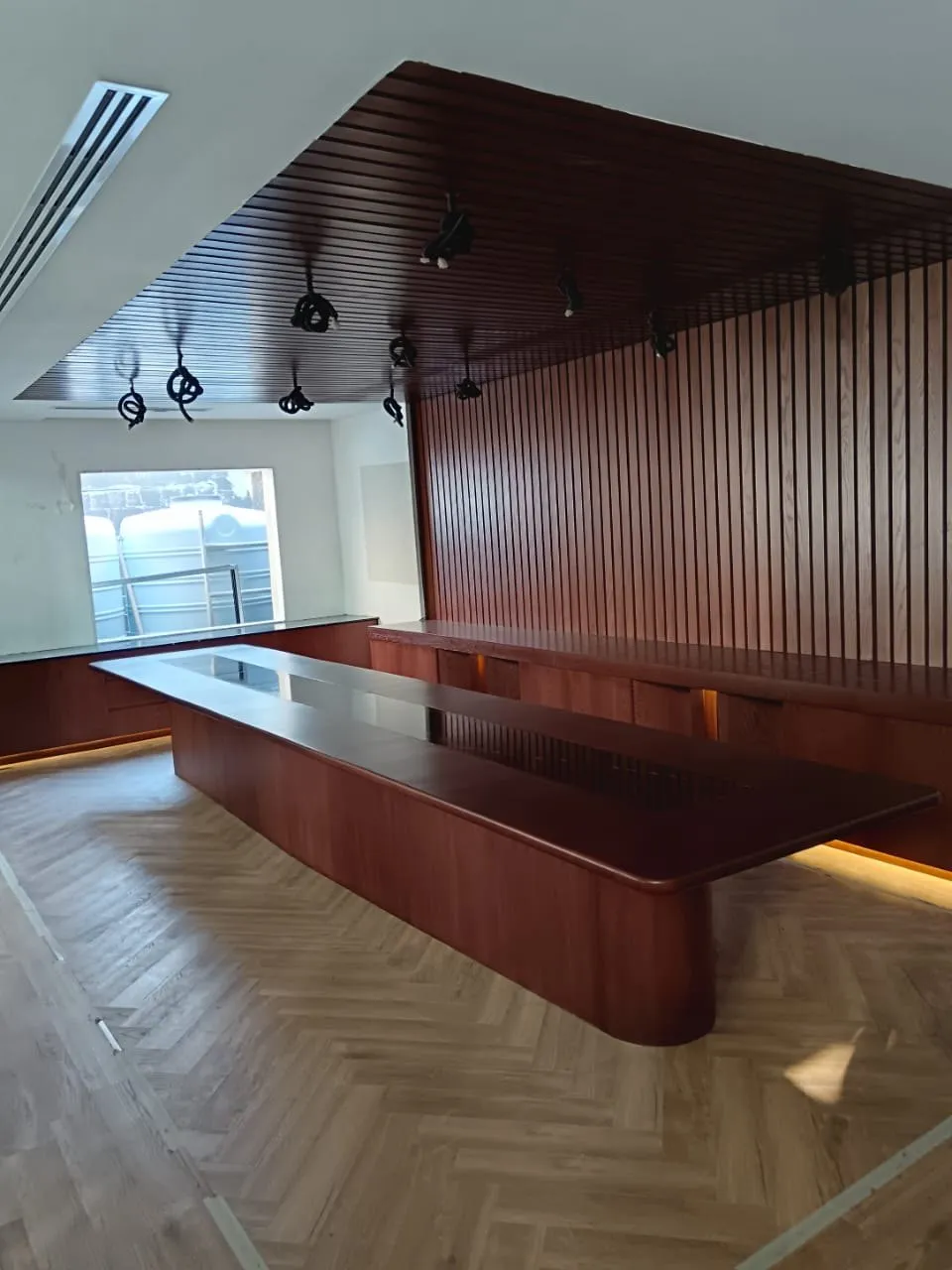 Boardroom with a dark walnut table with a marble inset, slatted wall and herringbone floor