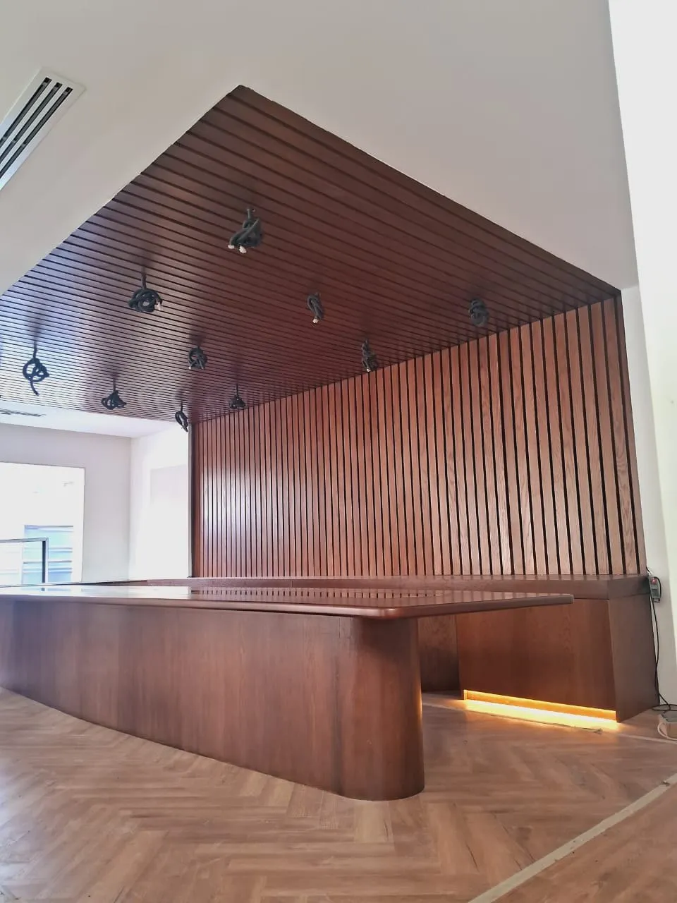 Wide view of a boardroom showing the slatted wall and the herringbone to marble floor transition