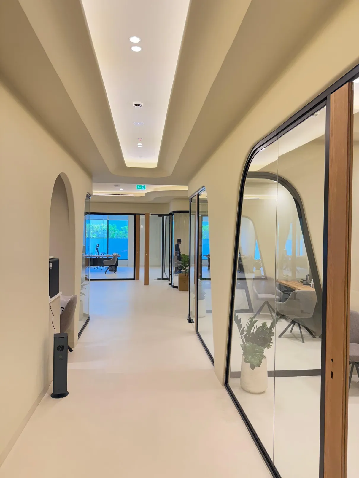 Office corridor with rounded glazed partitions and a cove lit ceiling