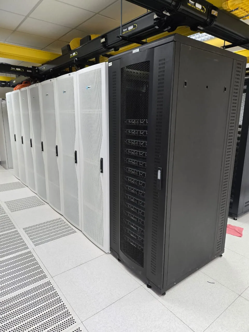 Row of network and server cabinets on a raised floor, fibre containment overhead
