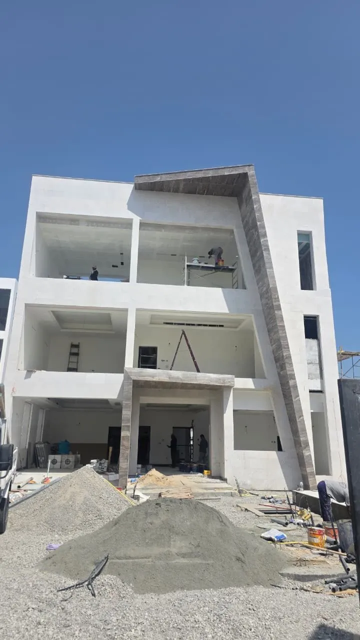 Full elevation of a near complete villa in stone cladding with crew on site