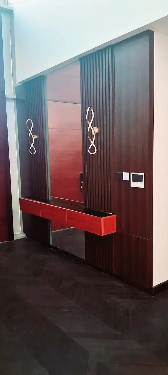 Entrance foyer in fluted dark timber with a red lacquer console and infinity sconces