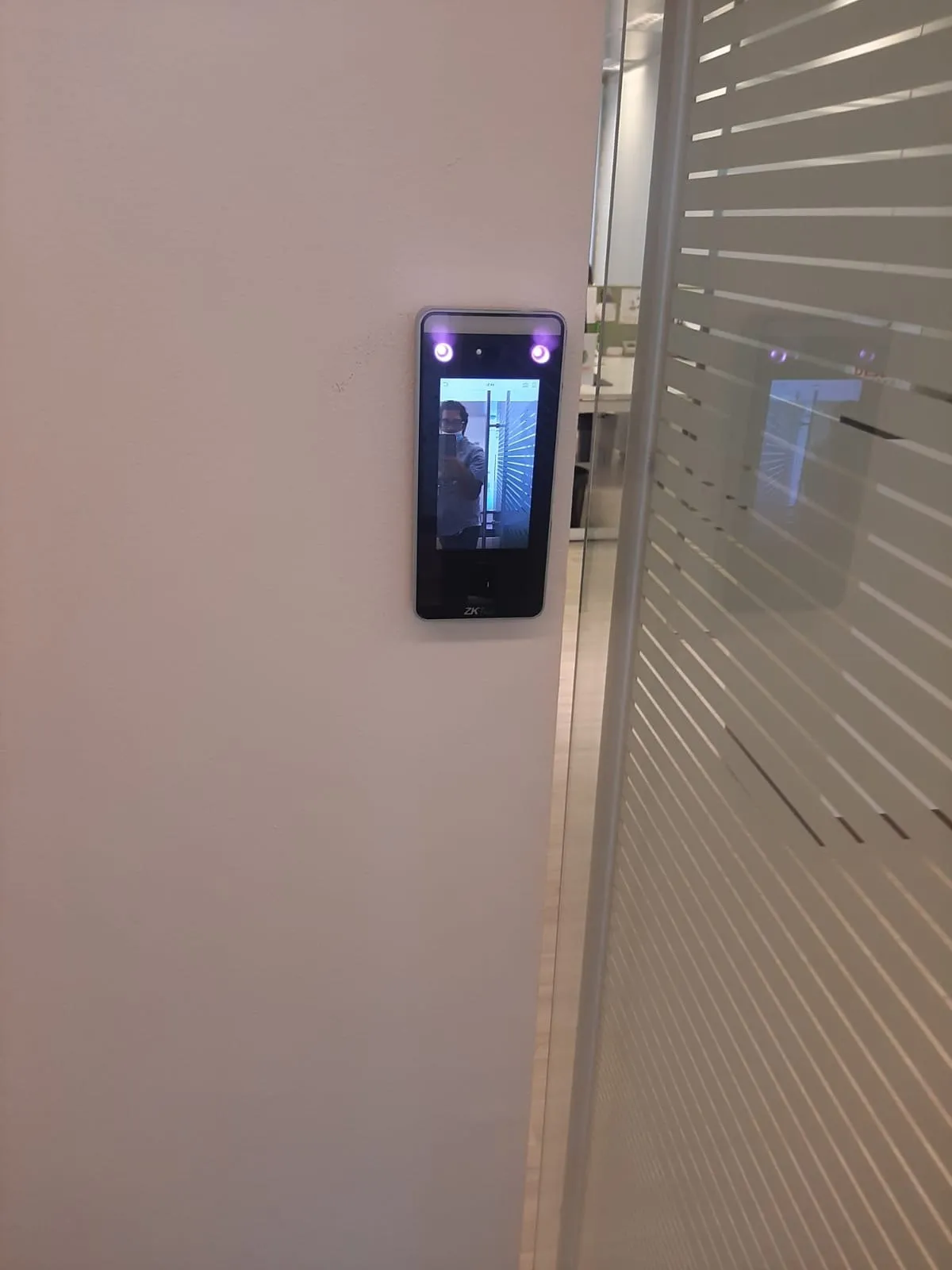 Face recognition reader mounted beside a frosted stripe glass partition