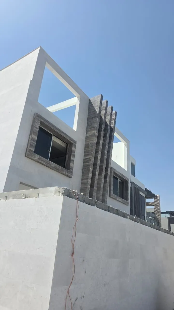 Fluted stone cladding fins at a facade corner against a clear sky