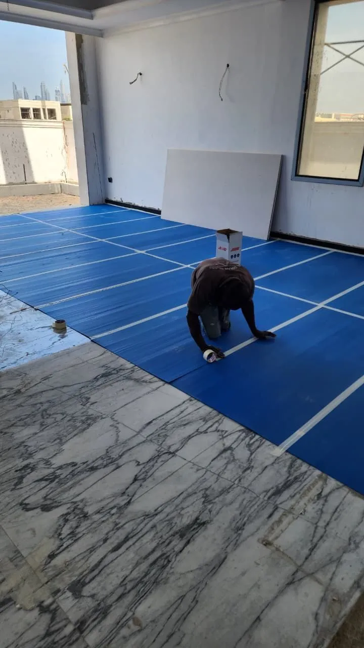 Worker taping protective sheeting over a finished marble floor