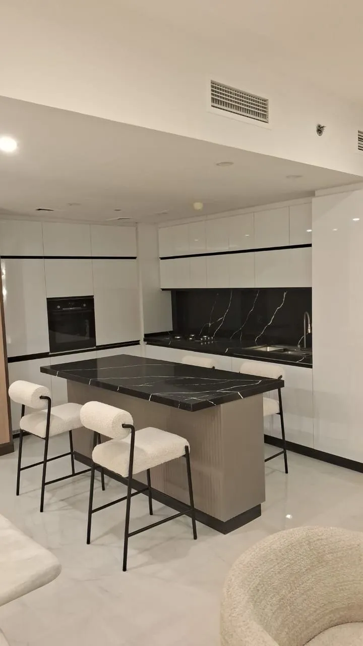 Open plan kitchen with a black veined marble island and boucle bar stools