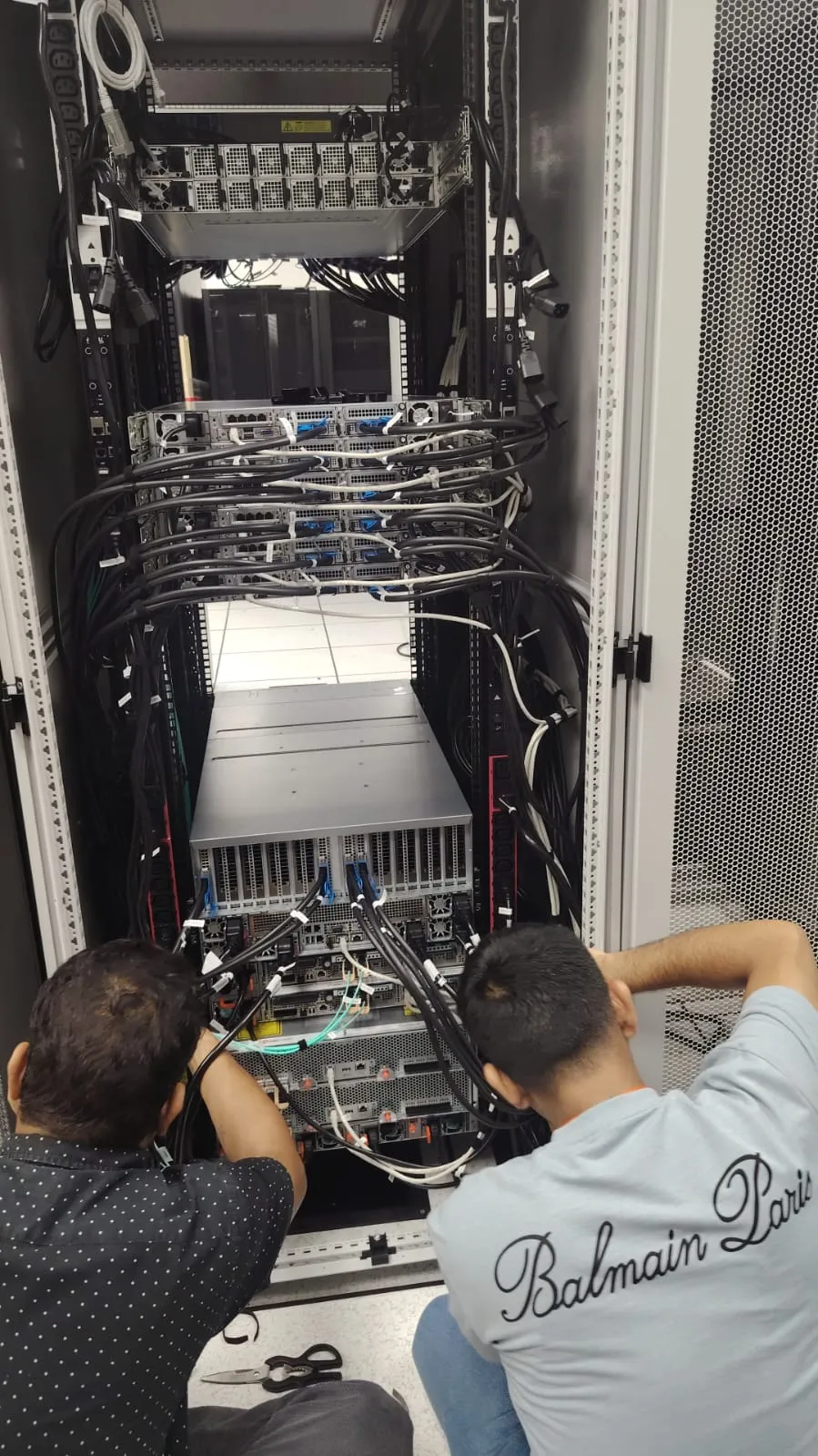 Two engineers cabling the rear of an open server cabinet