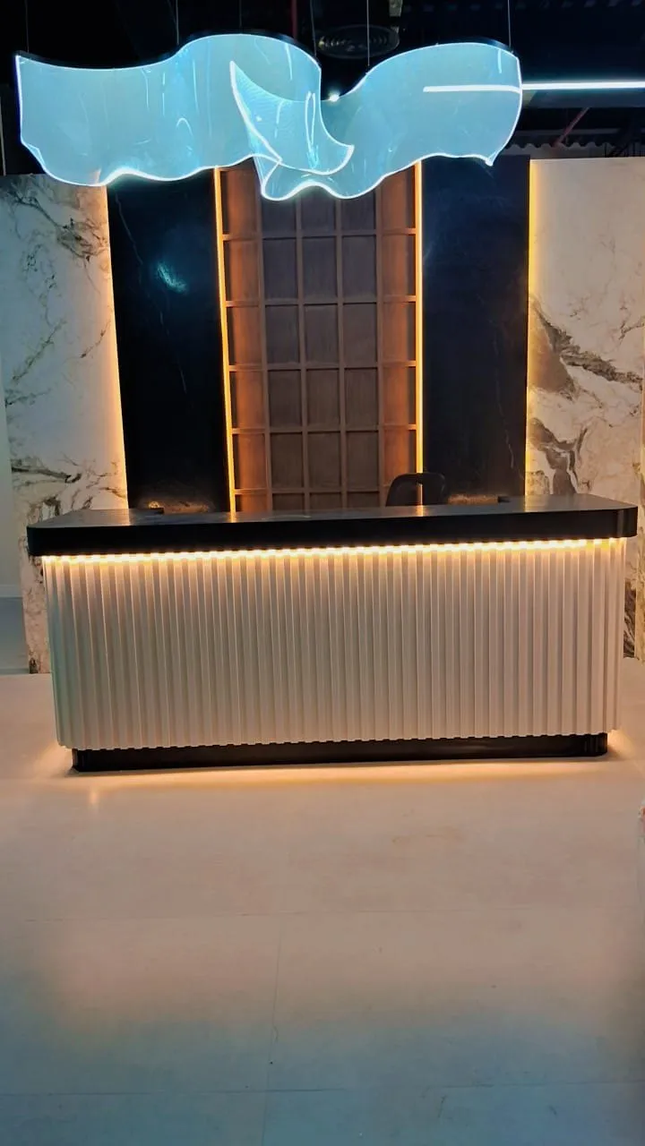 Reception desk seen head on beneath a sculptural acrylic ceiling feature