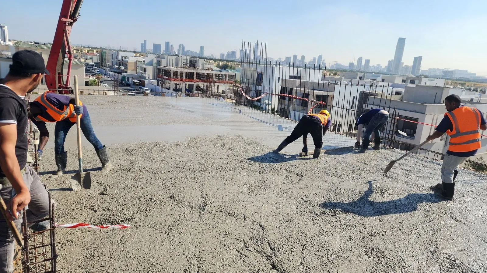 Crew screeding a freshly poured rooftop slab with the concrete pump boom overhead