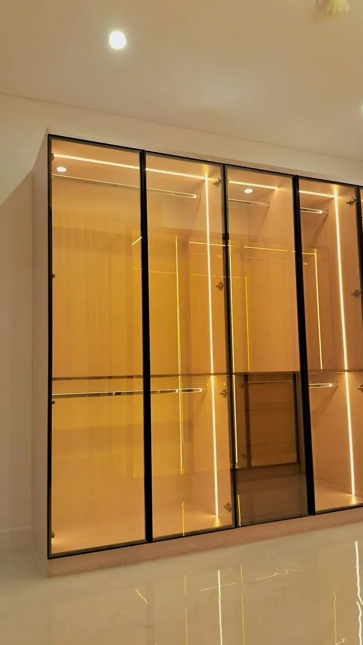 Walk in wardrobe with amber lit glass fronted bays